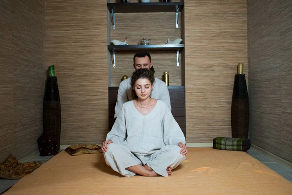 The massage therapist makes a Tibetan massage to a young woman. man and woman in white doing gymnastics. man and woman in white sitting in the lotus position and relax