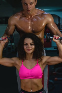 Spor hayatı. Zindelik. Spor salonu. Ateşli kıvırcık kadın. Yakışıklı vücut geliştirici. Spor salonundaki kaslı kadın ve erkek. Sportif çift. Vücut geliştirme.