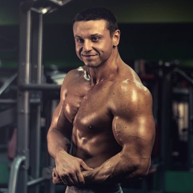 Spor salonundaki parmaklıklar üzerinde egzersiz yapan kaslı vücut geliştirici. Spor salonunda karın kası eğitimi almış yakışıklı, sportif ve seksi bir adam. fitness, vücut geliştirme, beslenme, sağlıklı yaşam tarzı