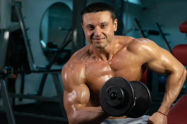 muscular bodybuilder doing exercise on bars in the gym. a handsome, sporty, sexy guy with a abs training in the gym. fitness, bodybuilding, nutrition, healthy lifestyle