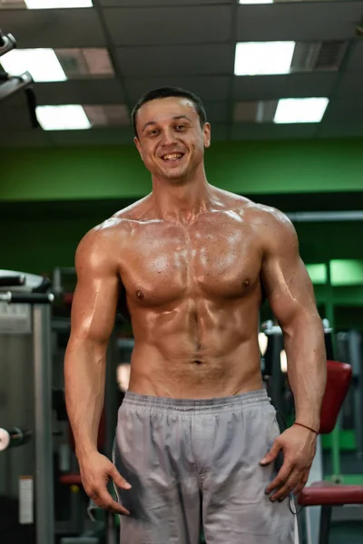 muscular bodybuilder doing exercise on bars in the gym. a handsome, sporty, sexy guy with a abs training in the gym. fitness, bodybuilding, nutrition, healthy lifestyle