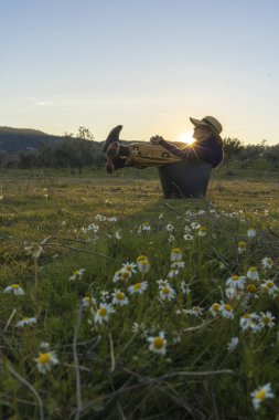 Hasır şapka alanında günbatımında oturan kadınla
