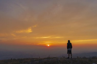 Gün batımında dağın zirvesinde adam silüeti
