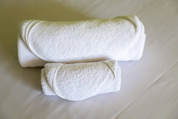 Hotel Towels Roll on the White bed in the Bedroom.