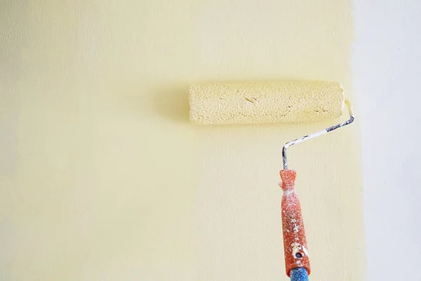 Rulo boya fırçası ışık sarı izole beyaz duvar boyama.