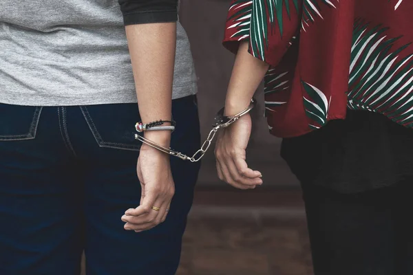 Couple Friend of Women under Arrest, Criminal Scence of Women get Caught with Handcuffed by the Policeman. Concept Picture of Prisoner or Slave.