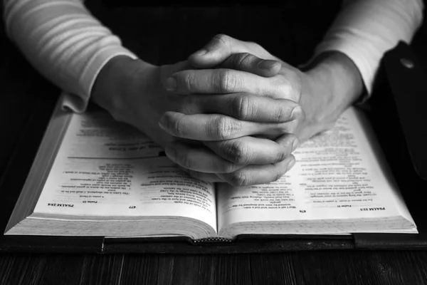 Adam onun İncil, siyah ve beyaz resim ahşap masa üzerinde İncil okuma ile dua ile Allah'a dua.