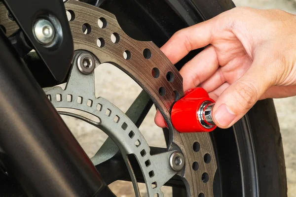 Man Using Motorcycle Disc Brake Lock to Secure His Motorcycle form Thief.
