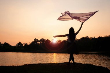 Girl Worship Jesus with Flag Dance in the Sunset at the River. clipart