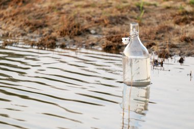 Gölde yüzen bir cam su şişesi