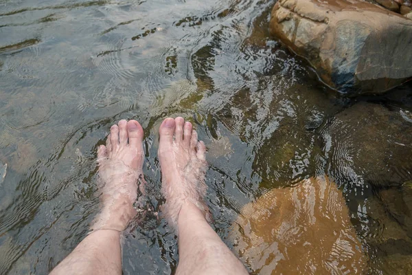 Muž Odpočíňující nohy ve studeném a čerstvém vodopádu. — Stock fotografie