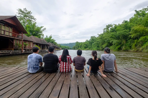 Gruppe von Freunden entspannt auf dem hölzernen Schwimmer über dem Fluss — Stockfoto