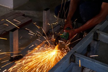 İnşaat alanında elektrikli tekerlek öğütme makinesi ile koruma üniforması olmadan Metal İnşaatı Kesen Güvensiz İşçi.