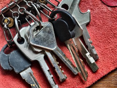 Kırmızı deri bir yüzey üzerinde çoklu metal ev anahtarlarının Macro yakın çekimi. Klasik güvenli anahtar düzenleyici, ev güvenliği sembolü, erişim ve koruma.