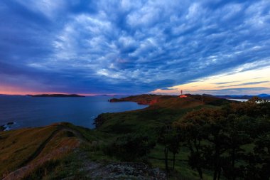 Cape Bruce Slavyanka, içinde Khasansky ilçe Primorsky Krai renkli şafakta. Cape Bruce - bu yüksek kayalıklarla, berrak denizi ve yeşil çim tepeler üzerinde