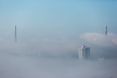 Tuman Vladivostok şehir içinde. Sisin içinde gizli Rus ve altın köprü dikmesi.