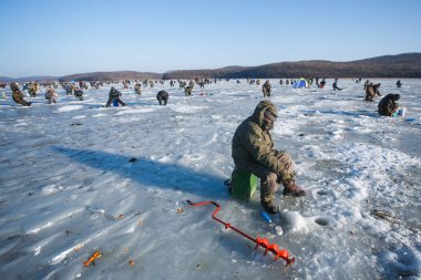 Ocak 2013 - Rus Adası, Vladivostok - Erkekler buzda ve balıkta oturur. Rusya 'da kış balıkçılık.