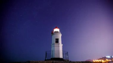 Vladivostok'taki Tokarevsky deniz feneri. Zaman Turları. Yıldızlı gökyüzü ve gemenida geçen göktaşı dere arka planda Tokarev deniz feneri