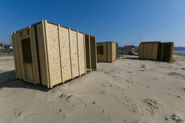 Kumlu deniz plajında rekreasyon merkezi için evlerin inşaatı. Denizde bir tatil alanı inşaatı.