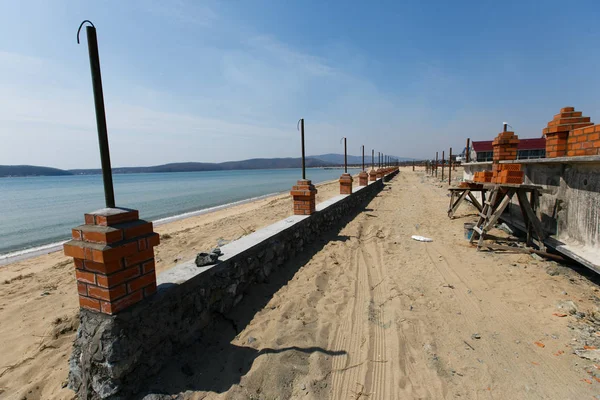 Construction of houses for the recreation center on the sandy sea beach. Construction of a resort area on the sea.