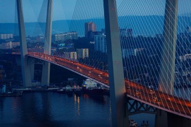 Altın Askılı köprü yol araç trafiği yukarıdan. Modern Vladivostok Rusya gece aydınlatma. Eski ve modern Merkez binaları.