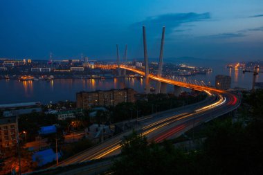 Altın Askılı köprü yol araç trafiği yukarıdan. Modern Vladivostok Rusya gece aydınlatma. Eski ve modern Merkez binaları.
