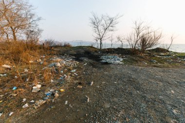 Deniz sahilinde çöp yığınları. Bölgenin kirlenmesi. Sahilde çöplük.