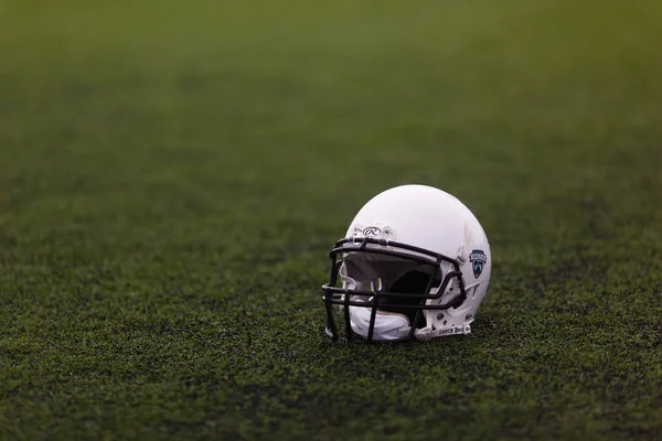 Protective white helmet for the game of American football (rugby) lies on the green grass on the sports field