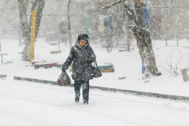 Aralık, 2014 - Vladivostok, Primorsky Krai - Yaşlı bir kadın kaldırımda karda yürüyor, bastona yaslanıyor