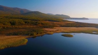 Güzel blagodatnoe gölü üzerinde uçan, arka planda yaz ve sonbahar ormanları ve dağlarla çevrili. Rusya'daki Sikhote-Alin Biyosfer Rezervi 1935 yılında Amur kaplanı nüfusunu korumak için kuruldu.
