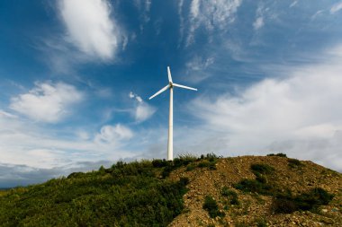 Güzel bulutlar ile mavi bir gökyüzüne karşı bir tepeüzerinde büyük beyaz yel değirmeni
