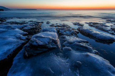 Güzel deniz manzarası. Buzla kaplı büyük kayalar şafak vakti deniz suyuyla doldu..
