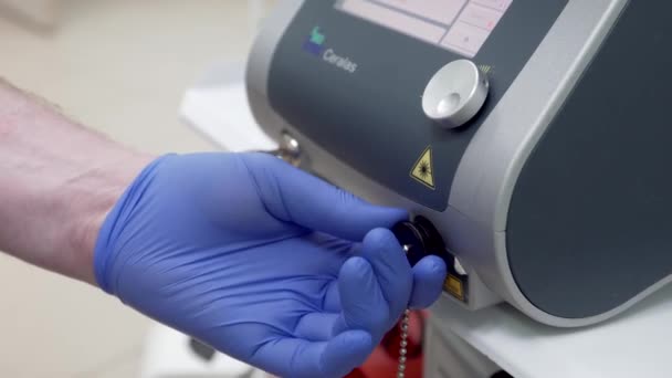 青いゴム手袋の医者は静脈を調べるために医療レーザーを巣にねじ込んだ — ストック動画