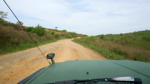 車のフロントウィンドウからの眺め 美しい景色を望む未舗装の田舎道に沿って大きな緑のジープが乗っています 車の観光 — ストック動画