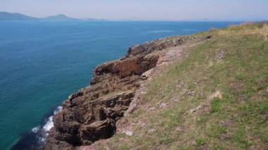 Güzel yaz deniz manzarası. Turkuaz deniz ve yeşil otların kayalık kıyılarının güzel manzarası.