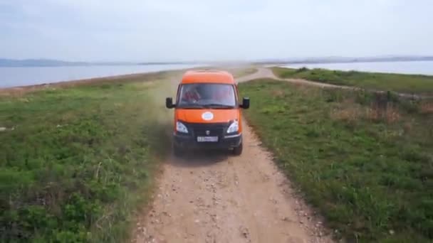 2019 沿海地方 ロシア オレンジ遠征ミニバス緑のフィールドの間のほこりっぽい未舗装の道路に沿って安定した運転 — ストック動画