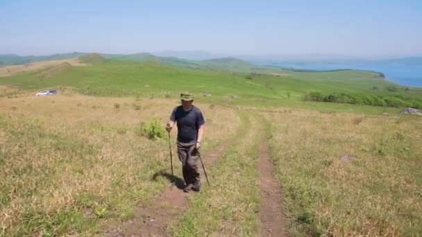 2019年夏天 俄罗斯普里莫尔斯基 克雷伊 一位年轻的男性游客 带着远足杆行走在绿地中的土路上 — 图库视频影像