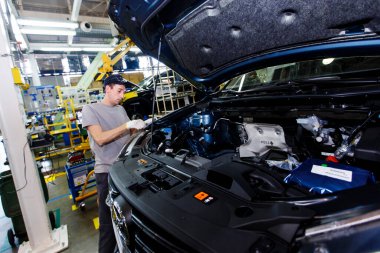 Yaz 2016 - Vladivostok, Primorsky Bölgesi - Bir otomobil fabrikasının çalışanı yeni bir arabanın kaputu altında motor monte ediyor