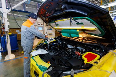 Yaz 2016 - Vladivostok, Primorsky Bölgesi - Bir otomobil fabrikasının çalışanı yeni bir arabanın kaputu altında motor monte ediyor