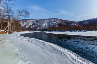 Primorsky bölgesinin kuzey manzarası, Samarga Nehri. Gün batımında ağaçlı tepelerin arka planında donmuş nehir.