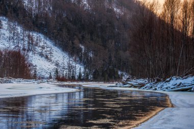 Primorsky bölgesinin kuzey manzarası, Samarga Nehri. Gün batımında ağaçlı tepelerin arka planında donmuş nehir.