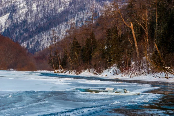 Primorsky bölgesinin kuzey manzarası, Samarga Nehri. Gün batımında ağaçlı tepelerin arka planında donmuş nehir.