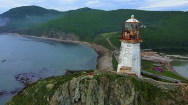 Yukarıdan bak. Rudny (Briner) deniz fenerinin üzerinde uçmak, berrak bir şafakta mavi denizin arka planına karşı dik bir uçurumun üzerinde durmak
