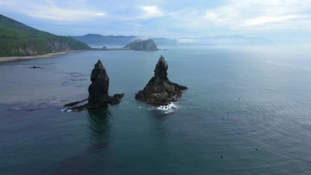 Blick von oben. Große Kekura Zwei Brüder mitten im Meer vor der Kulisse grüner Berge. — Stockvideo