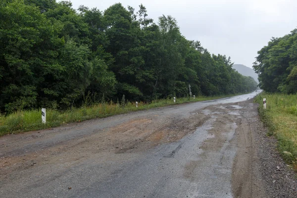 Very bad road in Russia. The asphalt road is all in holes in the middle of the forest.