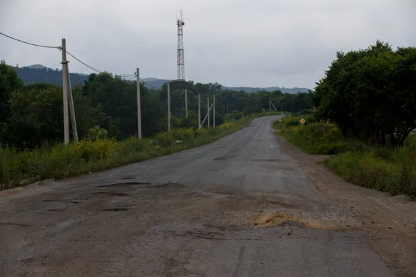 Drum foarte rău în Rusia. Drumul asfaltului este în găuri în mijlocul pădurii. . — Fotografie, imagine de stoc