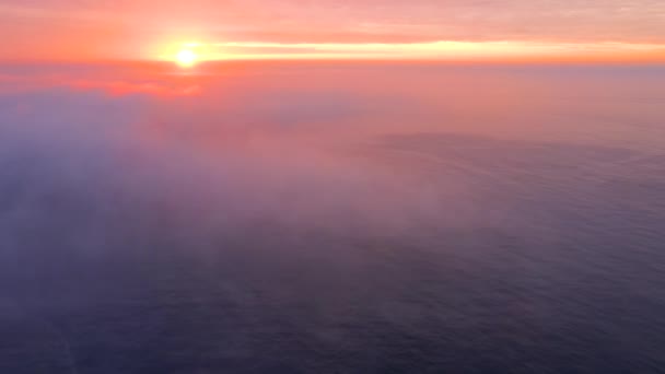 Вид сверху. Розовый туман распространяется по спокойному морю на рассвете — стоковое видео