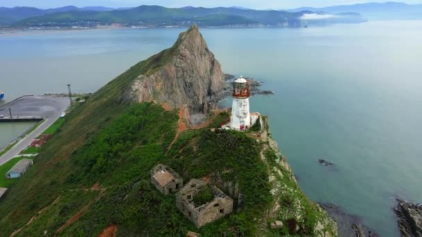 Vue d'en haut. Survolant le pittoresque phare de Rudny dans le village de Rudnaya Pristan, Territoire Primorsky. Repère du territoire de Primorsky — Video