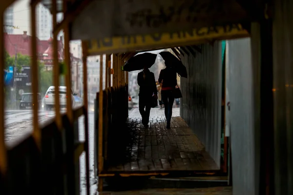 Мужчина ходит под зонтиком во время дождя, держа лицо за камерой — стоковое фото
