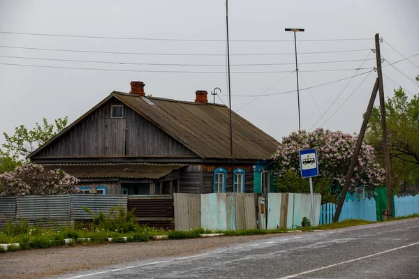 Una vecchia casa di legno si trova dietro una palizzata di legno — Foto Stock